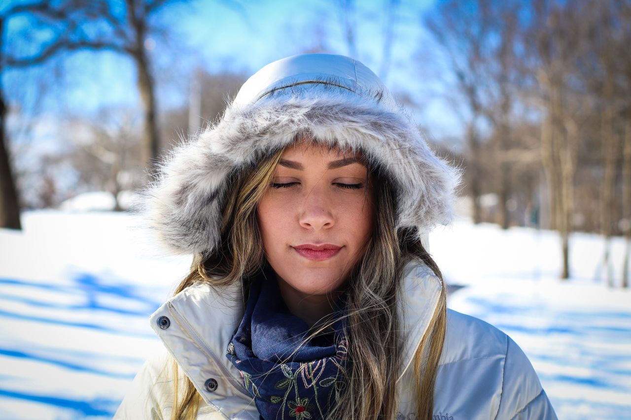 Woman in a fur-hooded winter coat standing in a snowy park