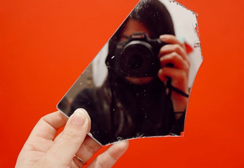 A person holding a camera in front of a broken mirror