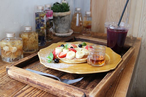 Free Pancakes garnished with fruits next to a Cup of juice Stock Photo