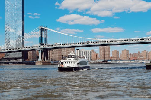 A ferry boat is traveling under the bridge