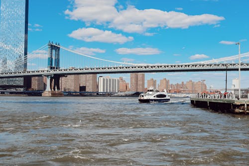 A boat is traveling under the bridge