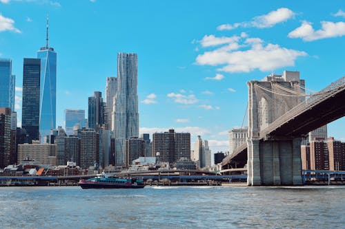 A boat is sailing under the brooklyn bridge