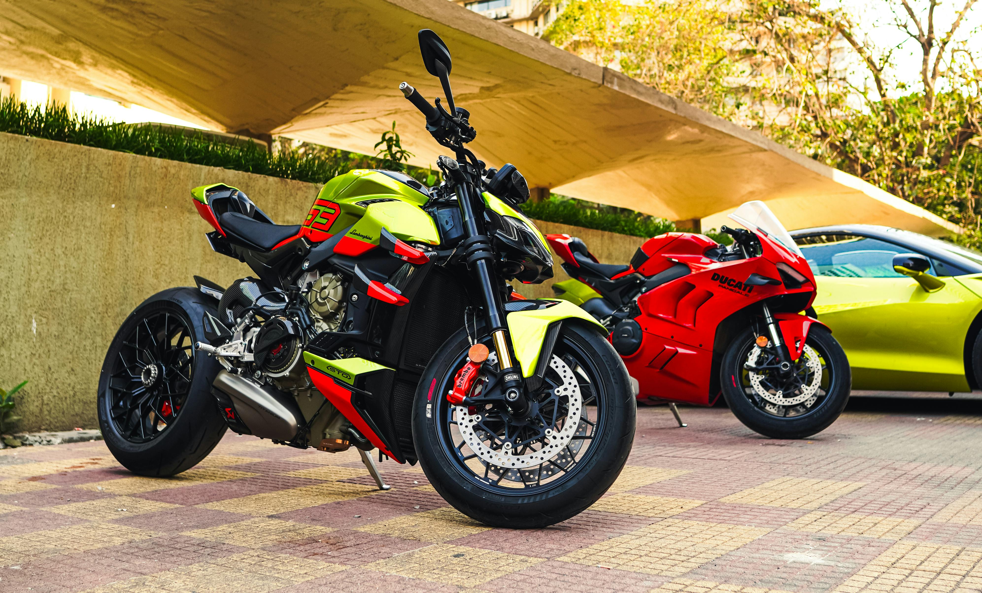Two vibrant Ducati motorcycles parked under a modern canopy on an urban pavement.