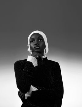 Striking black and white portrait of a woman in elegant attire and headwear.