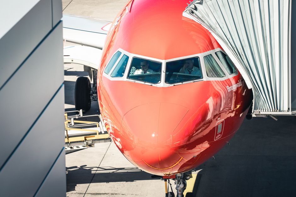 Front view of an Airbus A320-200 docking at Zurich Airport with pilots inside the cockpit.