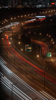 Stunning aerial view of city expressway at night with car light trails, capturing urban dynamism.