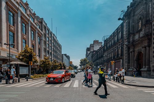 Free Vibrant city life in Ciudad de México as pedestrians and a police officer navigate a busy crosswalk. Stock Photo
