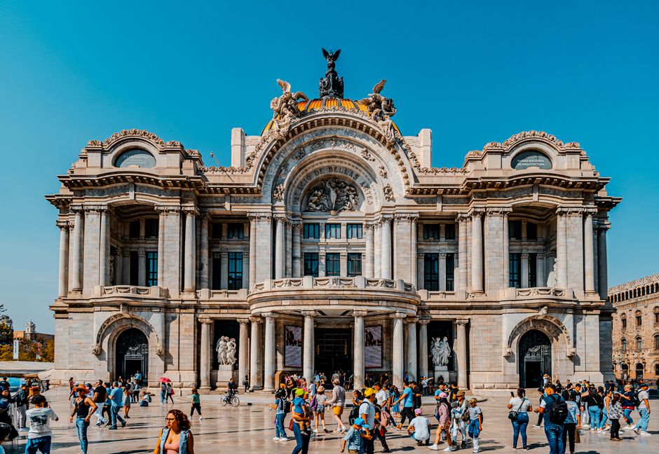 Multitudes se congregan cerca del icónico Palacio de Bellas Artes en la vibrante Ciudad de México, mostrando su impresionante arquitectura.