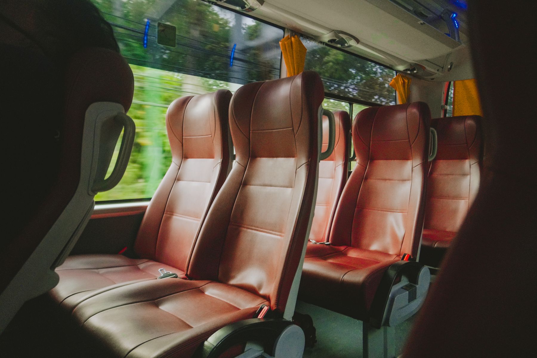 Interior de un bus con butacas reclinables tapizadas y pasillo central