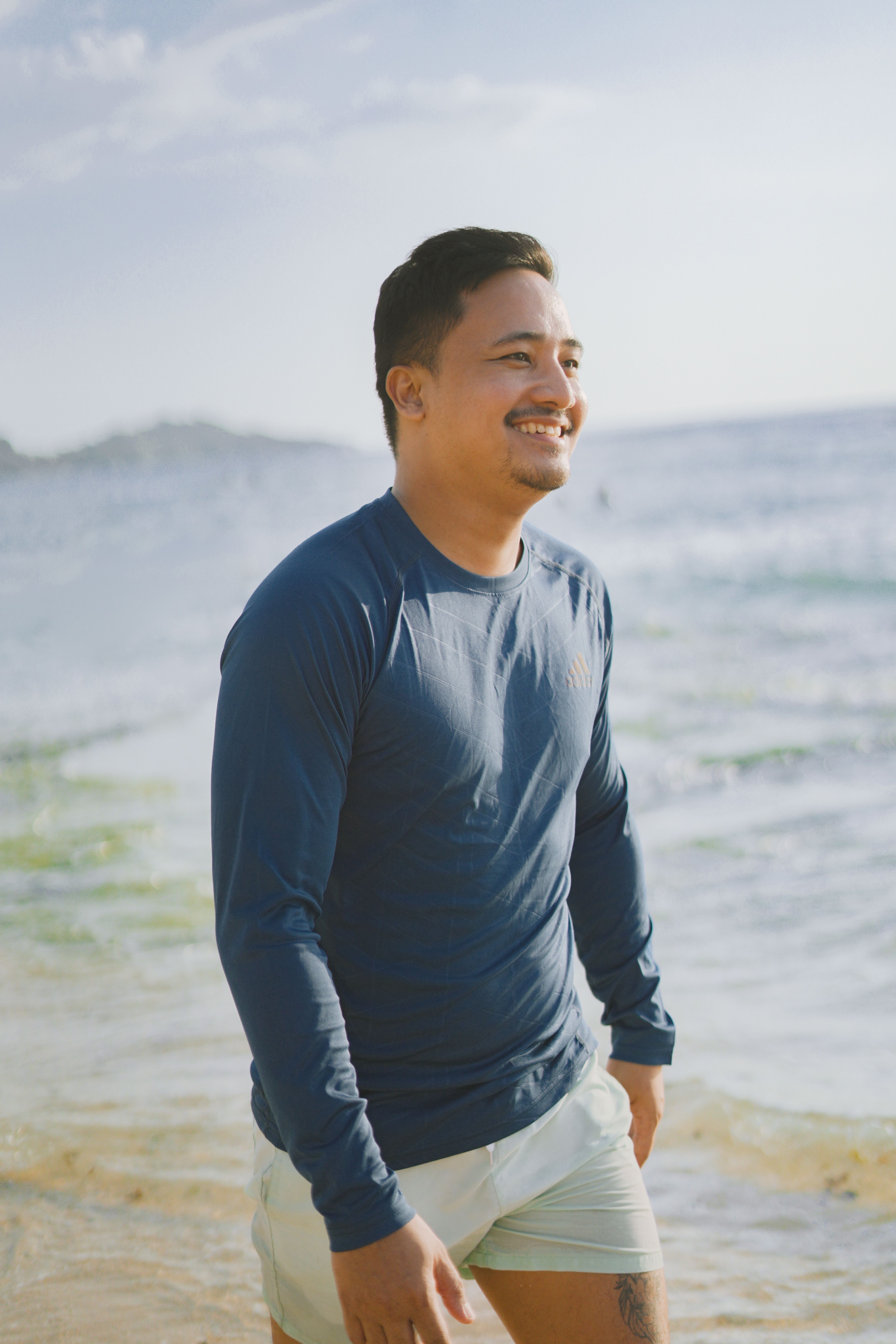Smiling man walking along a sunny beach on a summer holiday vacation