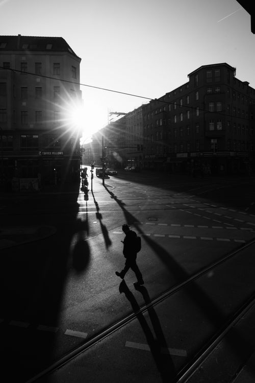 Free Silhouette of a person crossing a street during sunrise in Berlin's urban landscape. Stock Photo