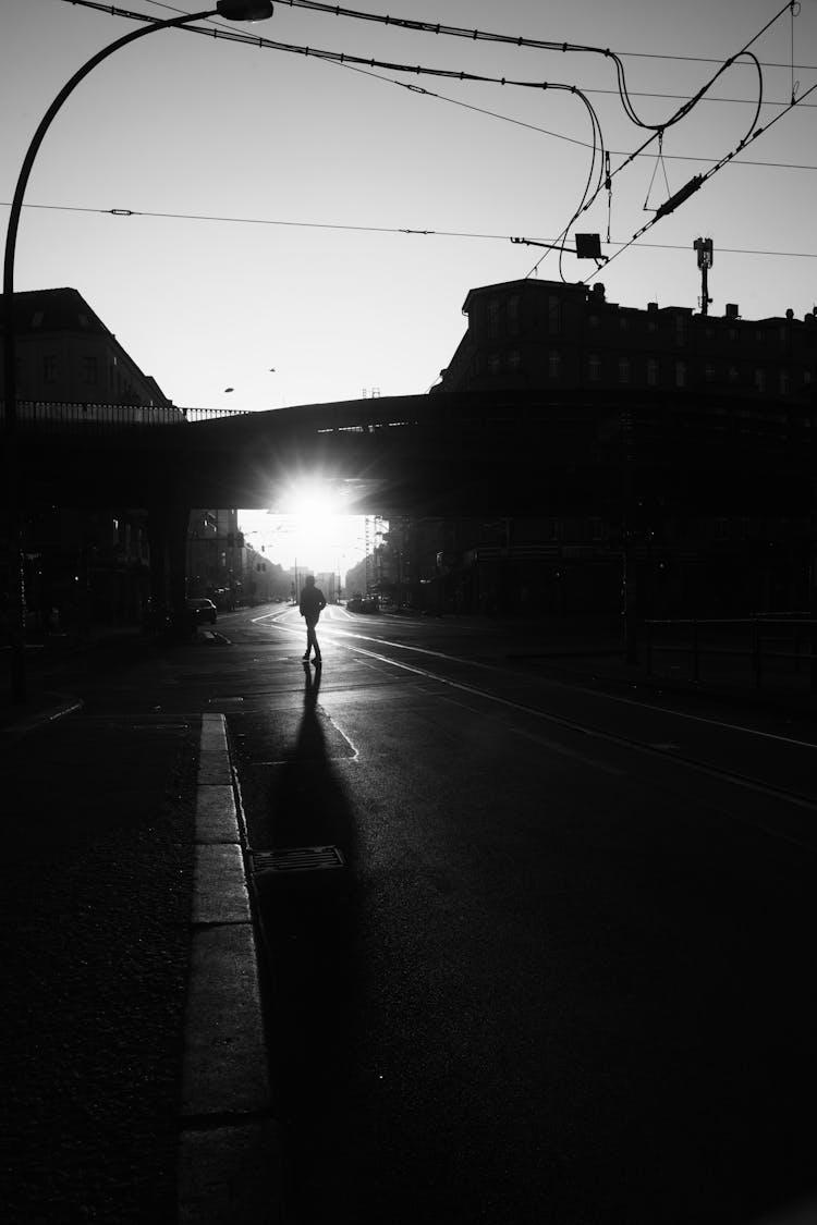 Silhouette Of Person On Street In City In Front Of Sun