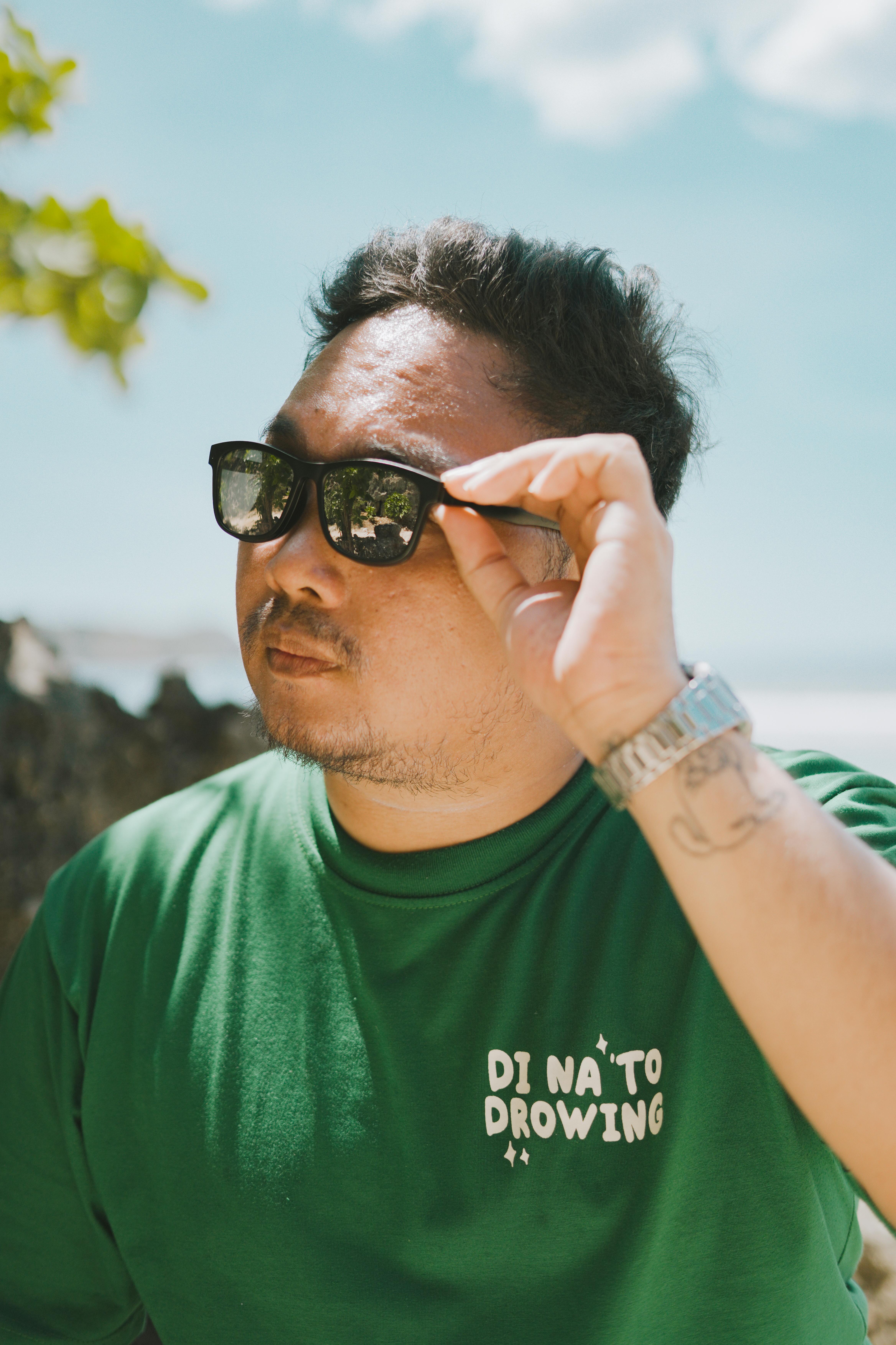 Man in green t-shirt and sunglasses at Bolinao beach, Philippines.