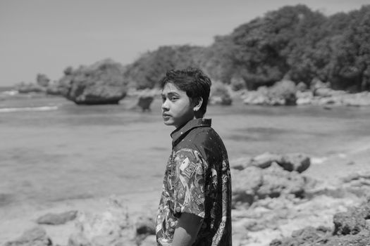 Monochrome portrait of a young man on the rocky beach of Bolinao, Philippines.