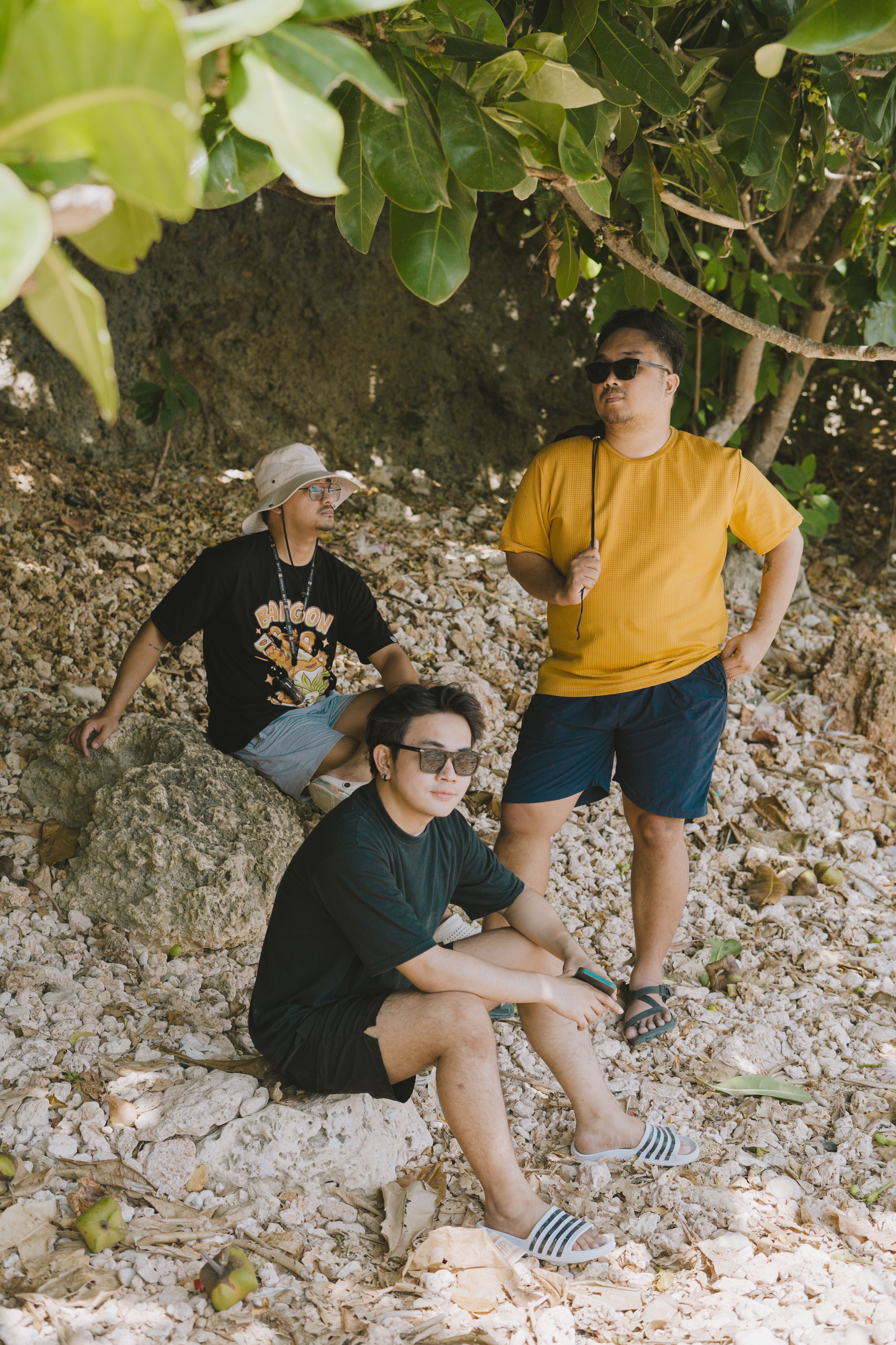 Three men lounging by the rocks in Bolinao, showcasing casual friendship in nature.