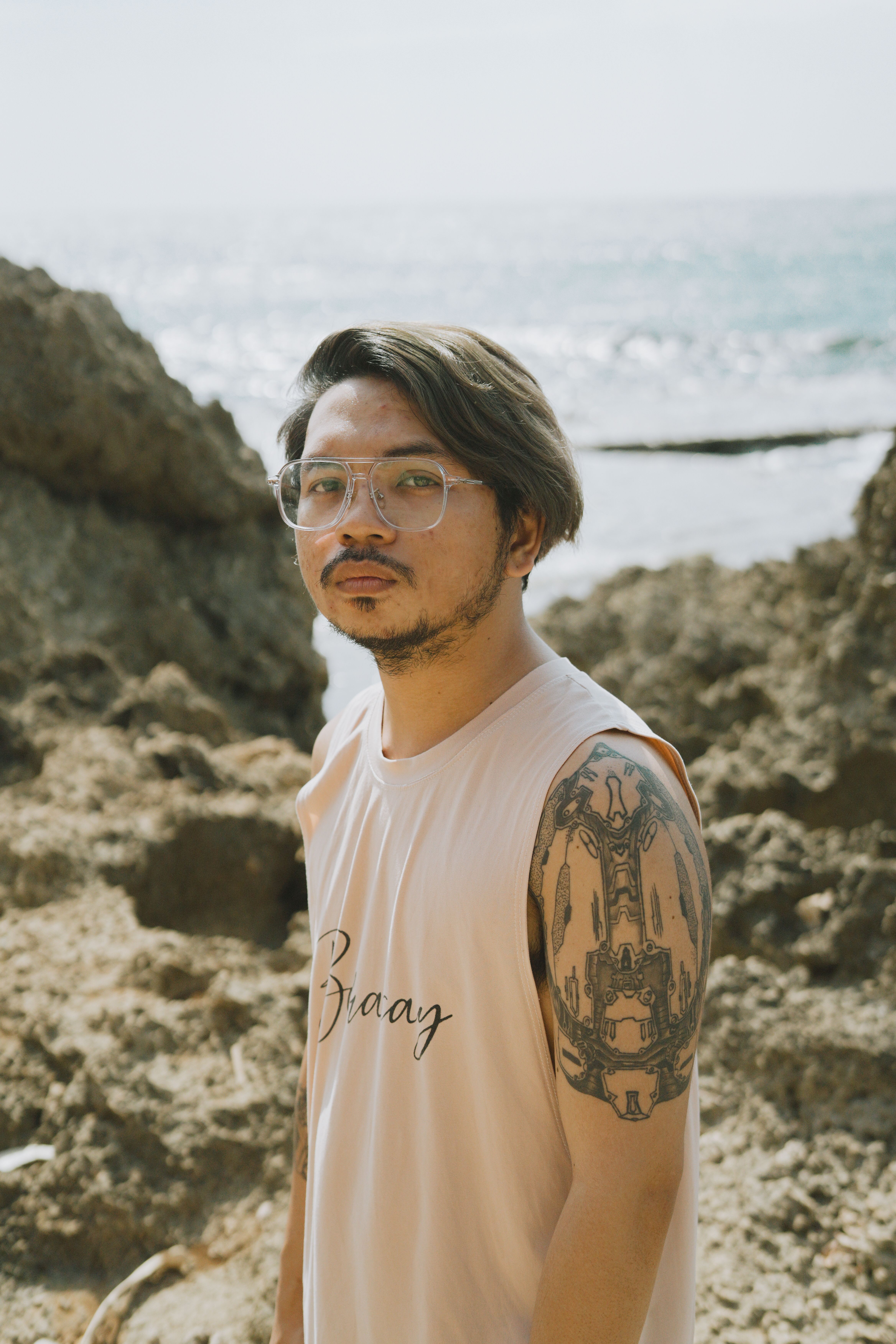 Young man with a tattoo standing by rocky seaside in Bolinao, Philippines.