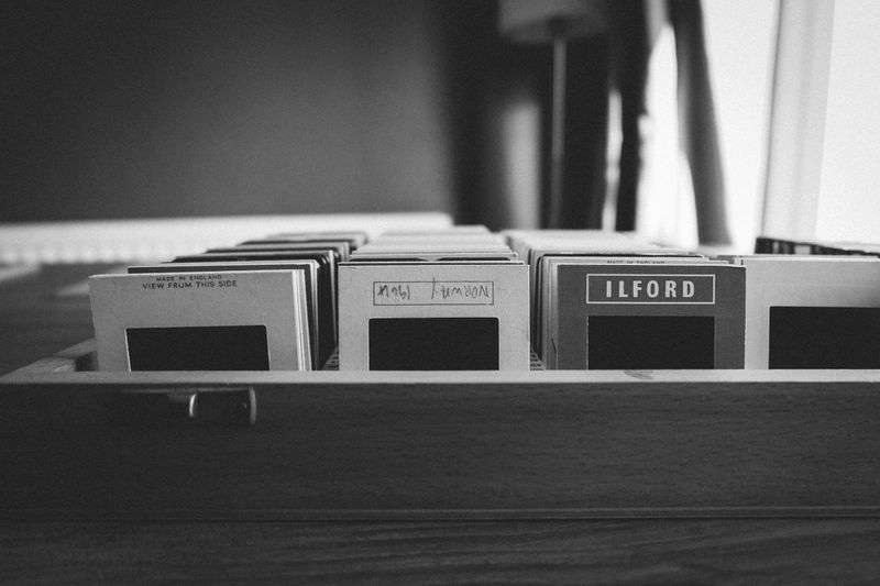 Black and white photo of vintage film slides organized in a wooden box.