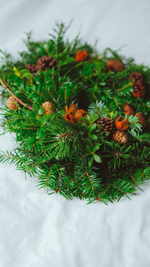 A wreath made of pine cones and berries on a bed