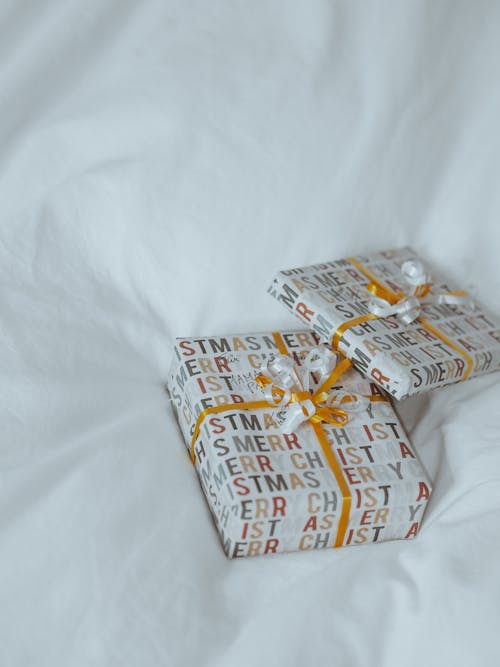 Two wrapped presents on a white bed