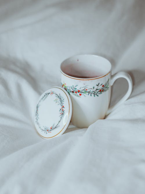 A cup and saucer on a bed with a blanket