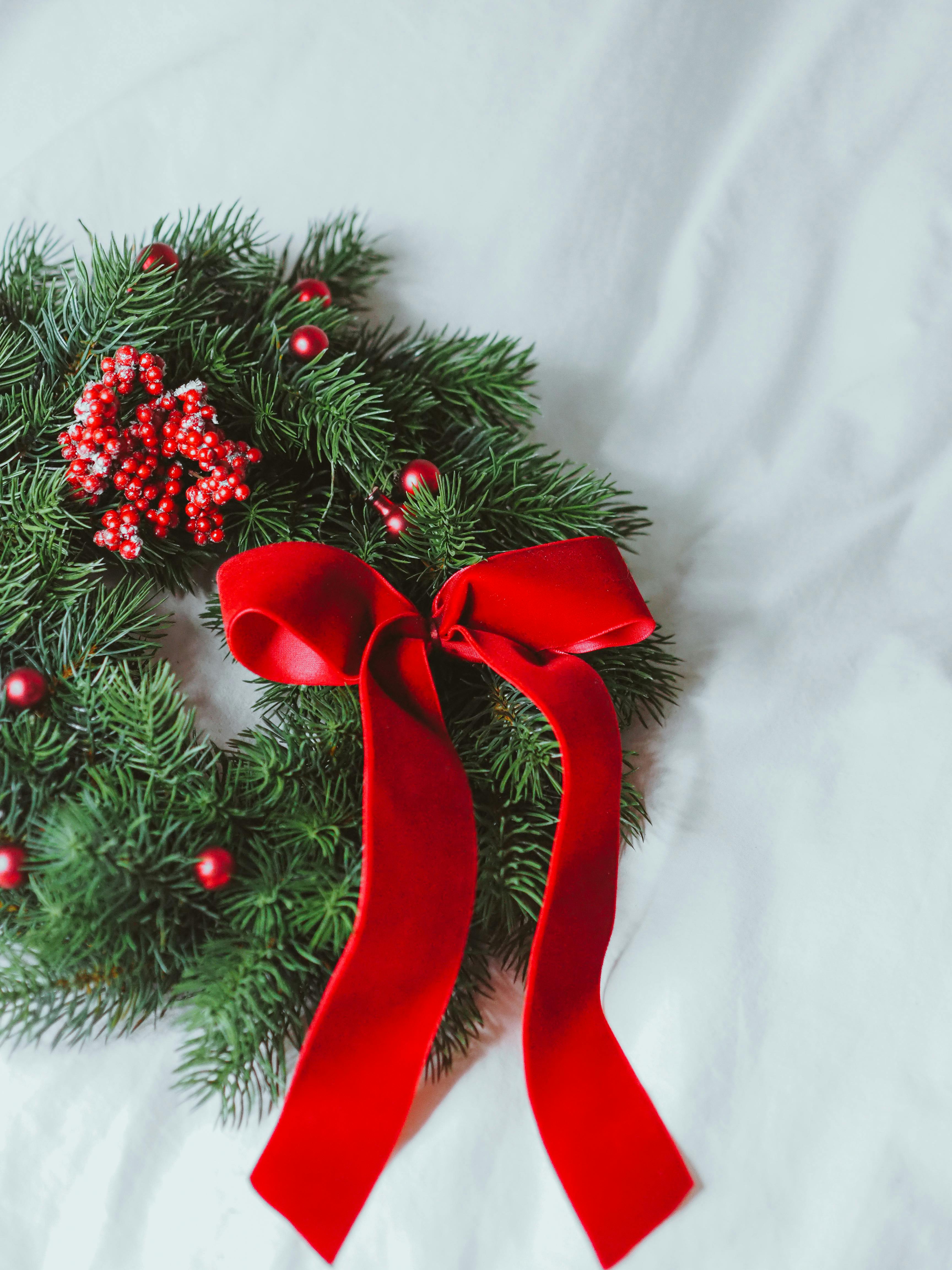 Beautiful Christmas wreath with conifer twigs and a red bow, perfect for holiday decoration.