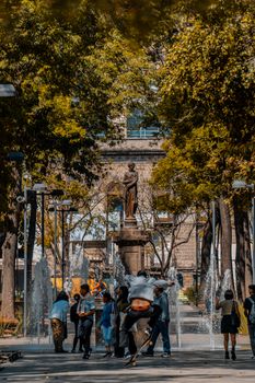 Vibrant scene showcasing people enjoying Alameda Central in Mexico City with fountains and sculptures.