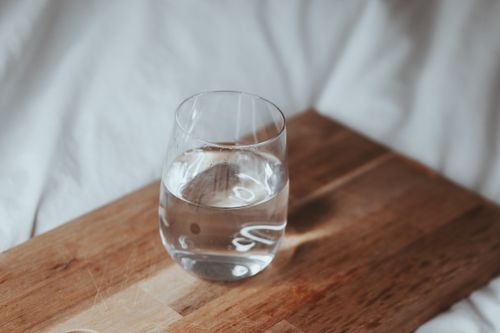 Free A refreshing glass of water placed on a wooden board, perfect for hydration. Stock Photo