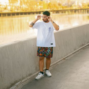 Young man posing in colorful streetwear by Manila waterfront. Vibrant, modern fashion captured in natural light.