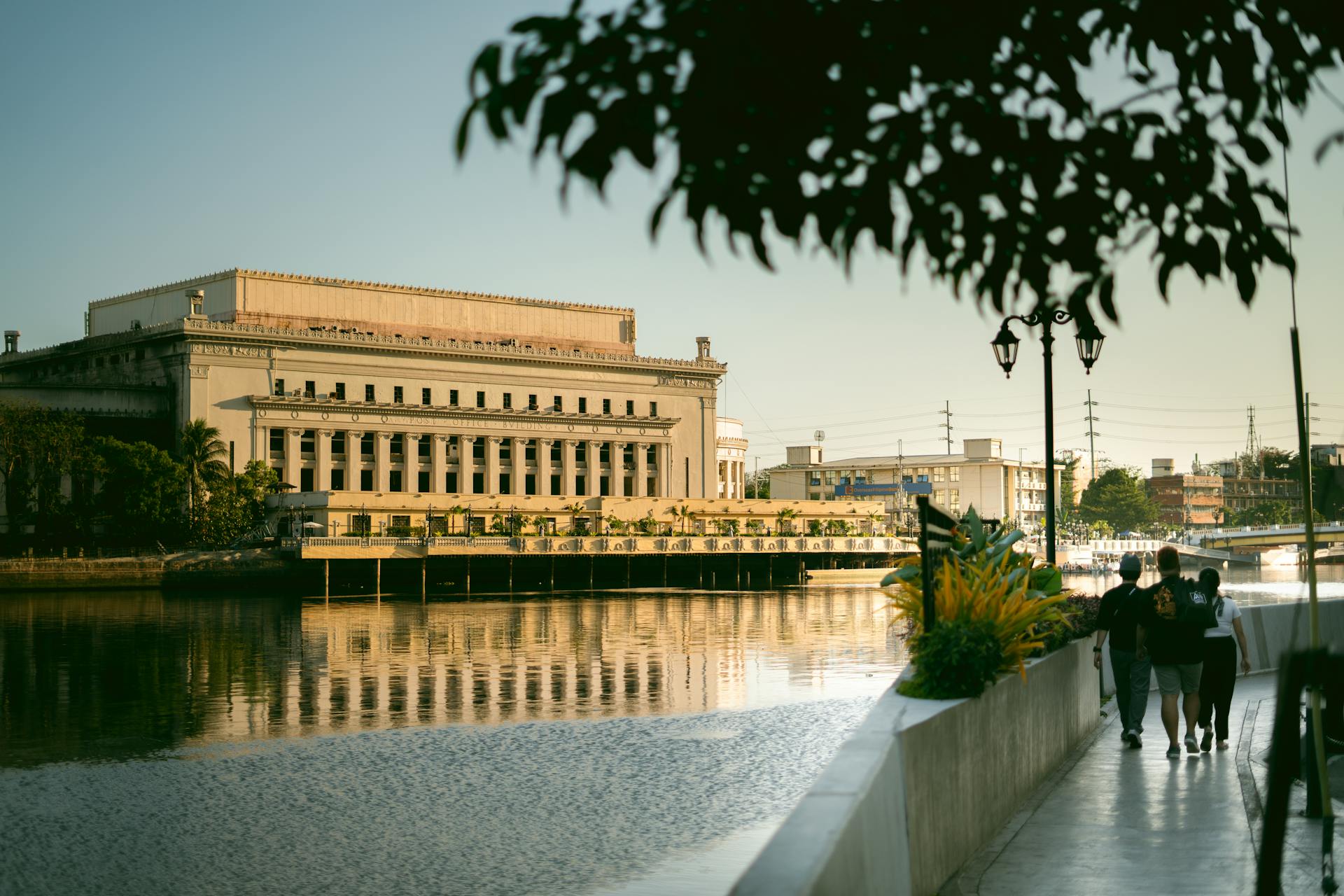 A serene view of the Manila Central Post Office building along the riverbank, capturing urban beauty at daytime.