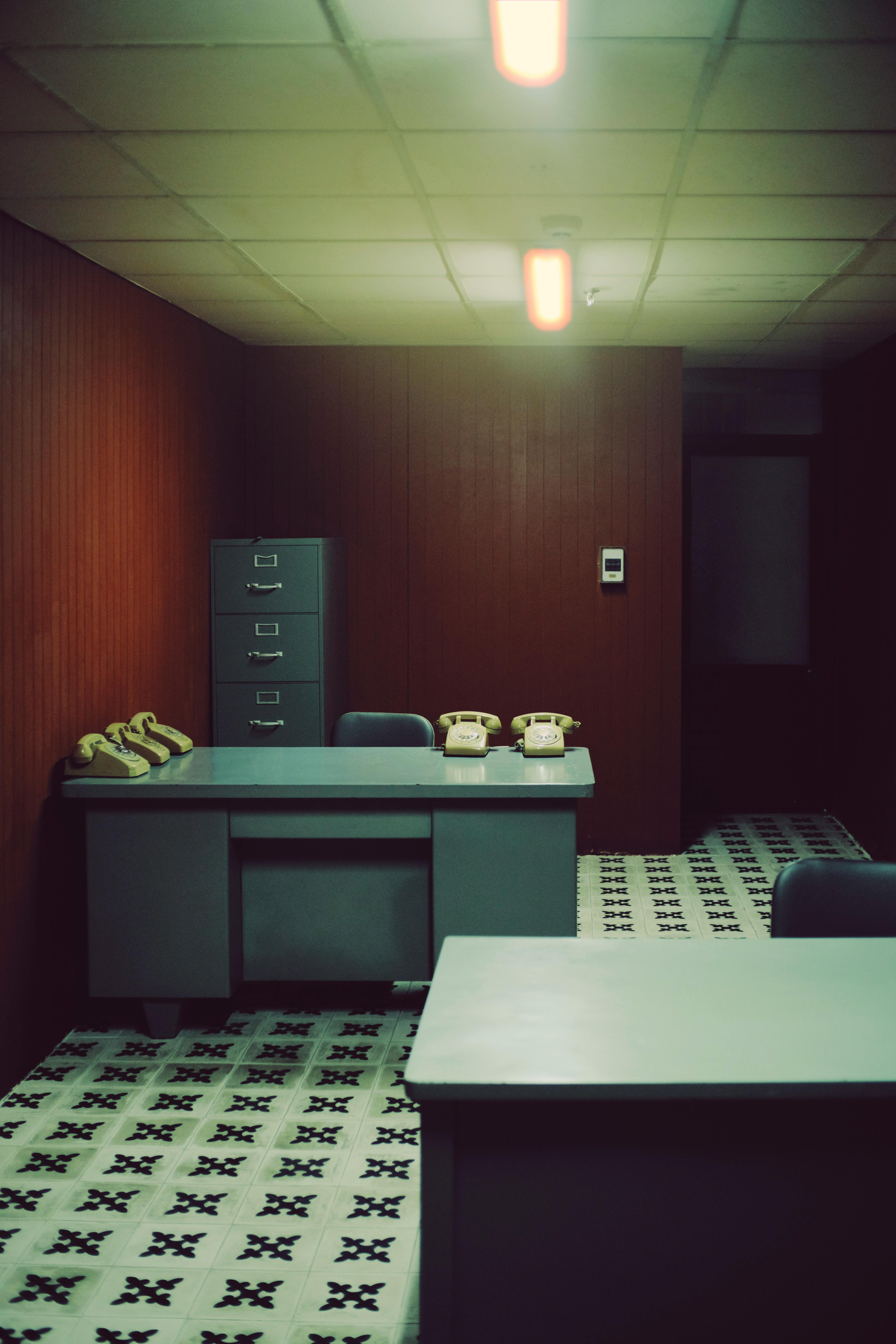 A vintage office with retro decor, showcasing old telephones and filing cabinets.