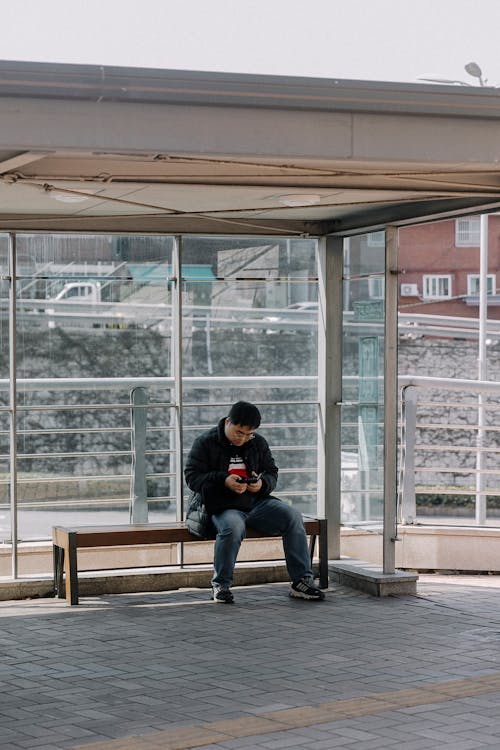 Základová fotografie zdarma na téma autobusová zastávka, bunda, džíny