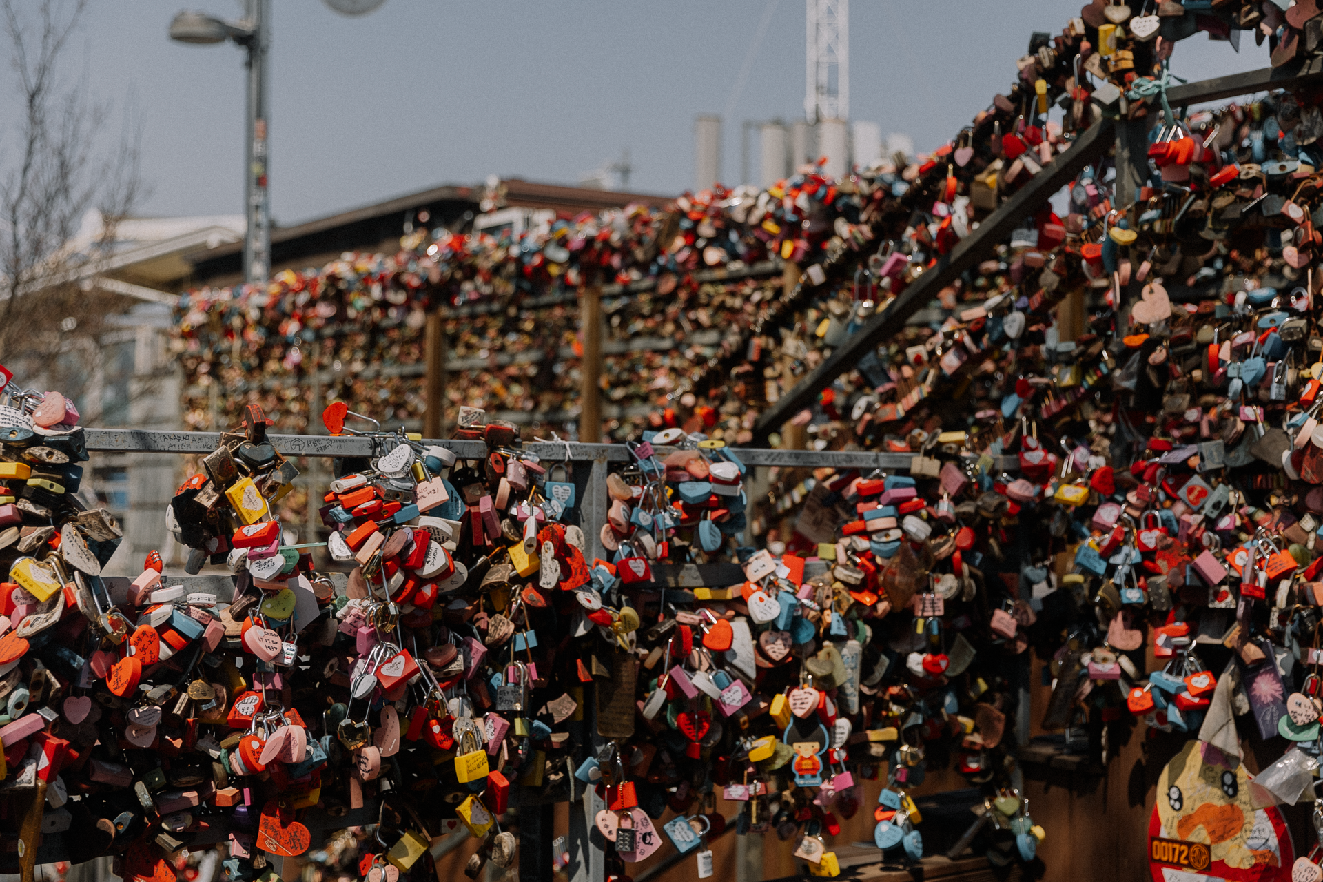 Colorful love locks densely covering a bridge railing in an urban setting, symbolizing commitment.