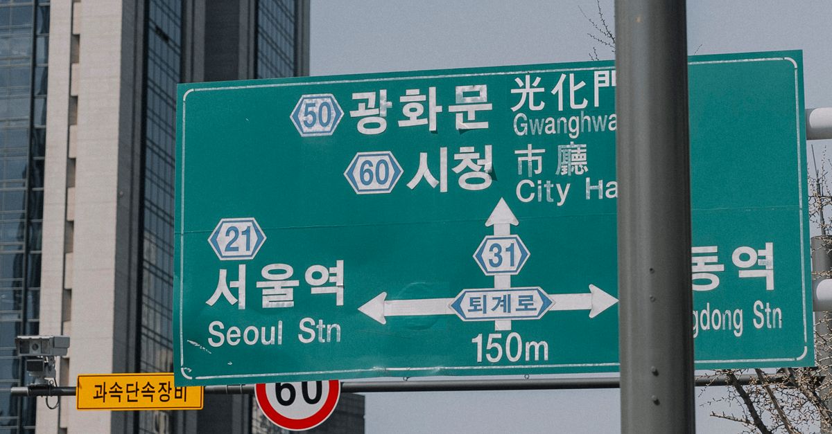 Traffic and directional signs in downtown Seoul with skyscrapers in the background.