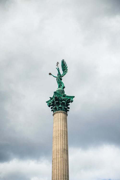 A green statue on top of a tall column