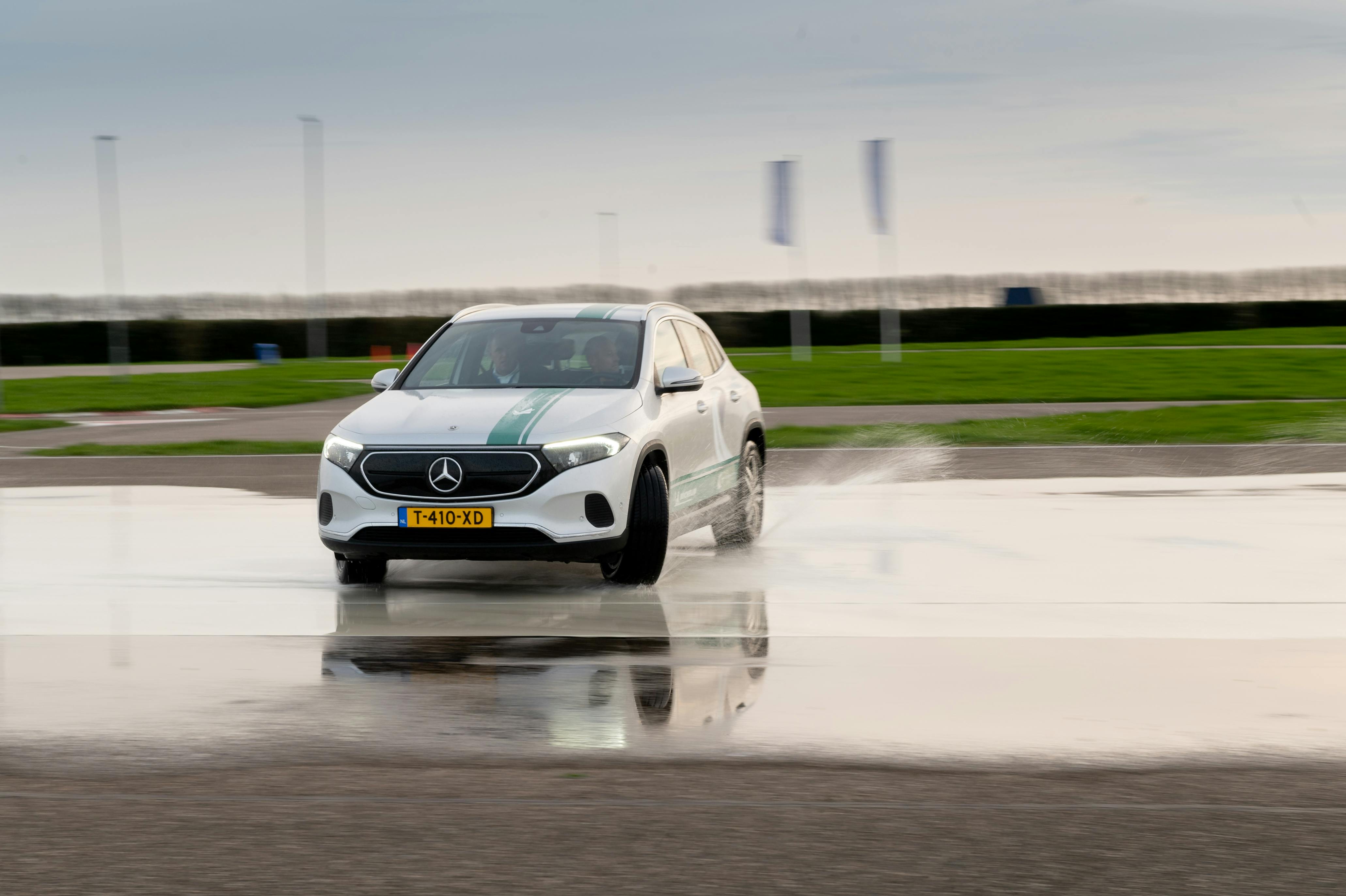 A silver Mercedes driving on a wet track with splash effect showcasing skid control technology.