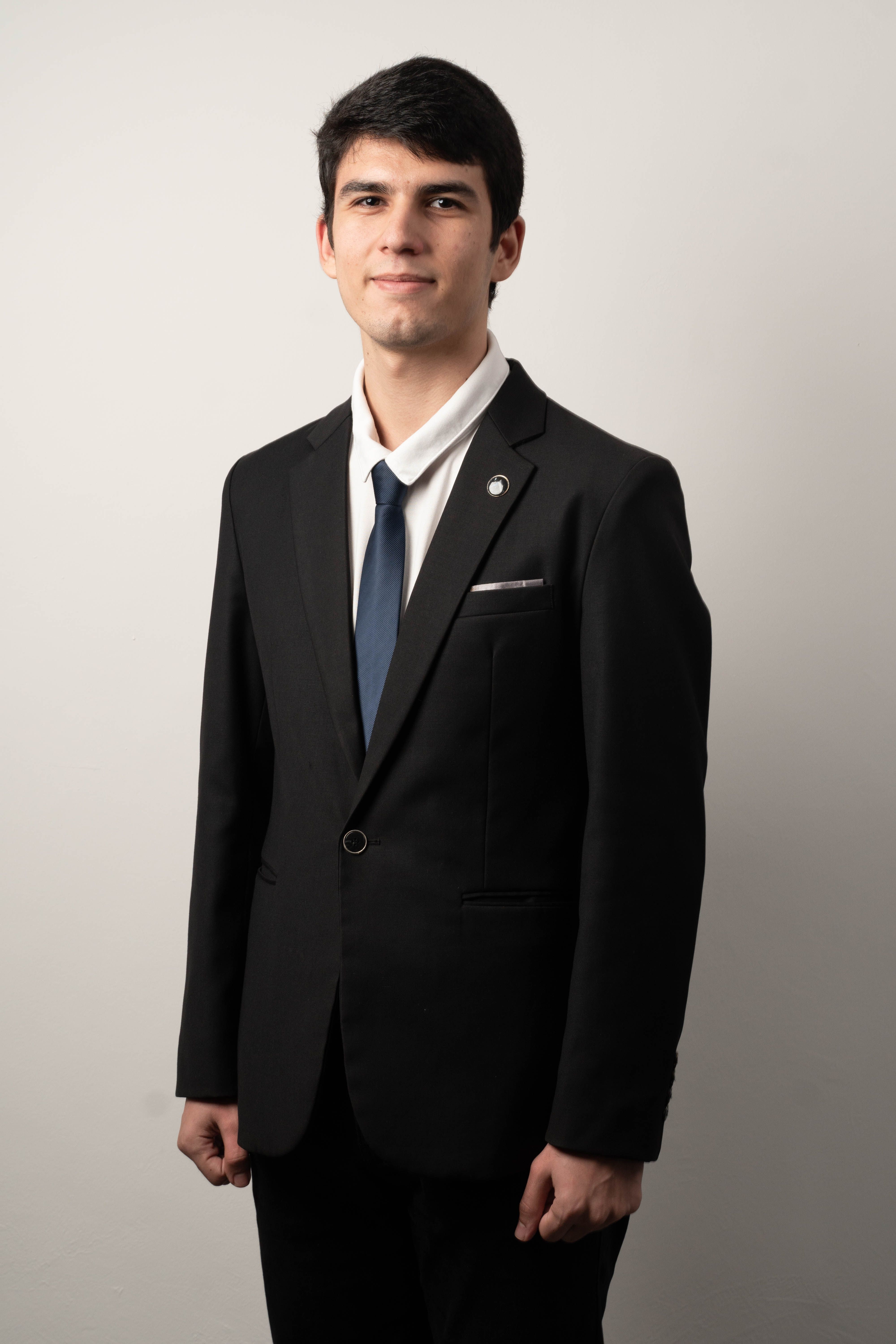 Studio portrait of a young man in a formal suit, elegantly dressed with a necktie.