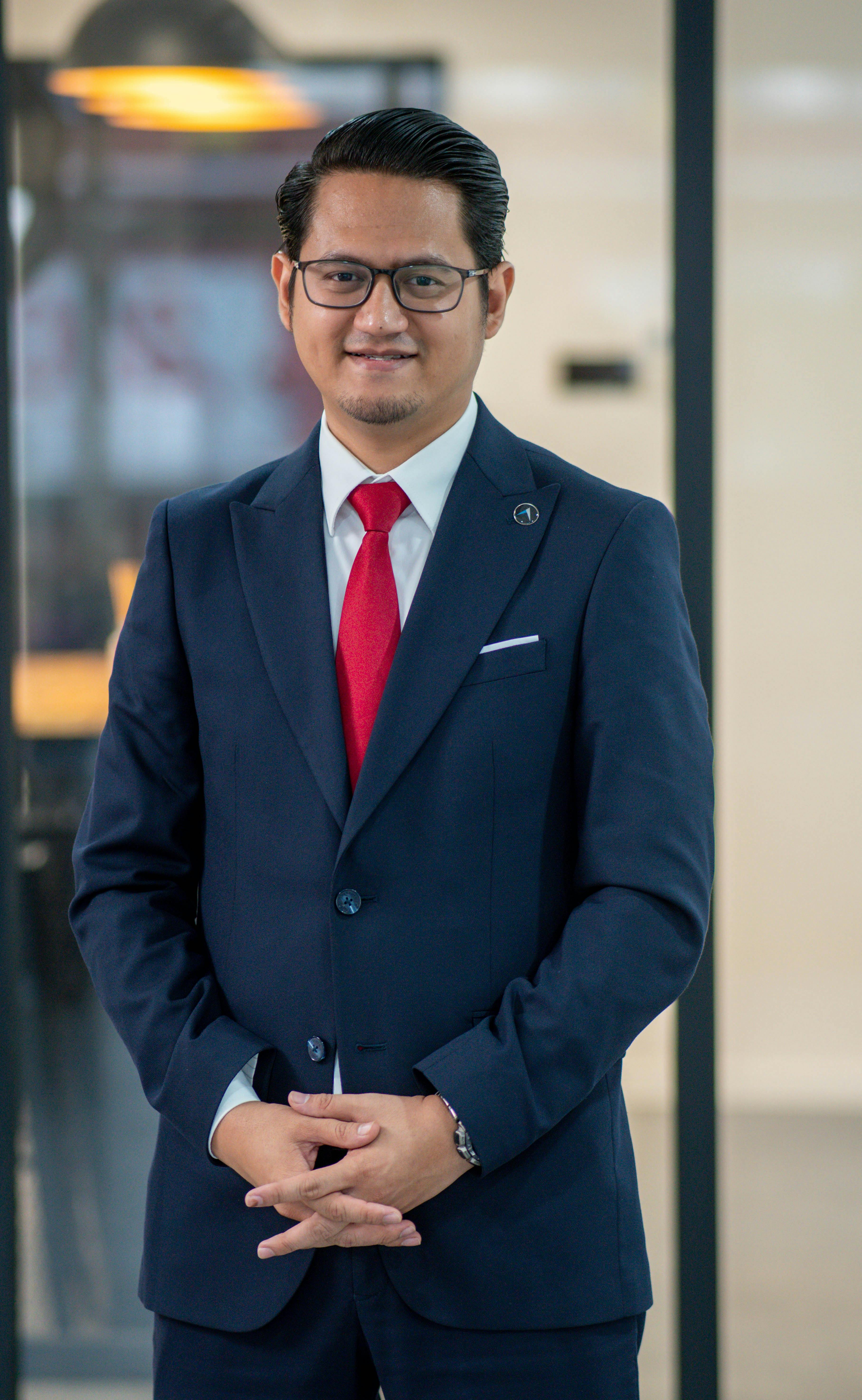 Confident businessman in a formal suit standing in a modern office environment.