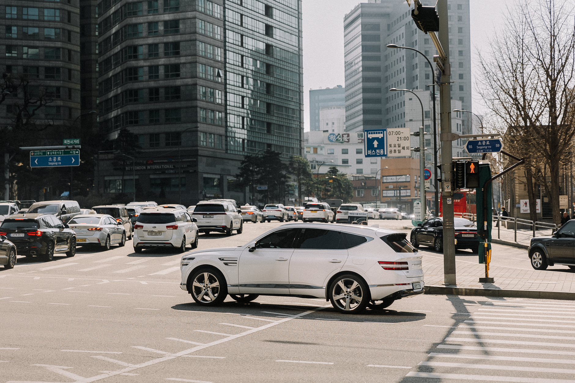 Urban traffic scene with a white car and skyscrapers under daylight.