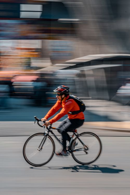 Free Blurred image of a cyclist in motion, navigating city streets with speed and precision. Stock Photo