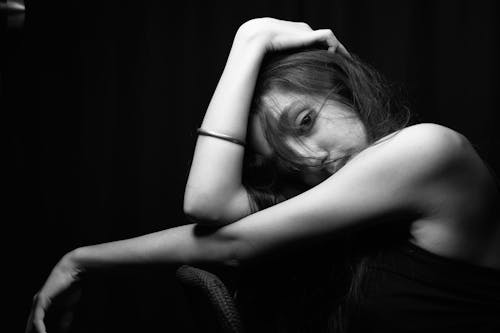 A woman sitting on a chair with her head in her hands