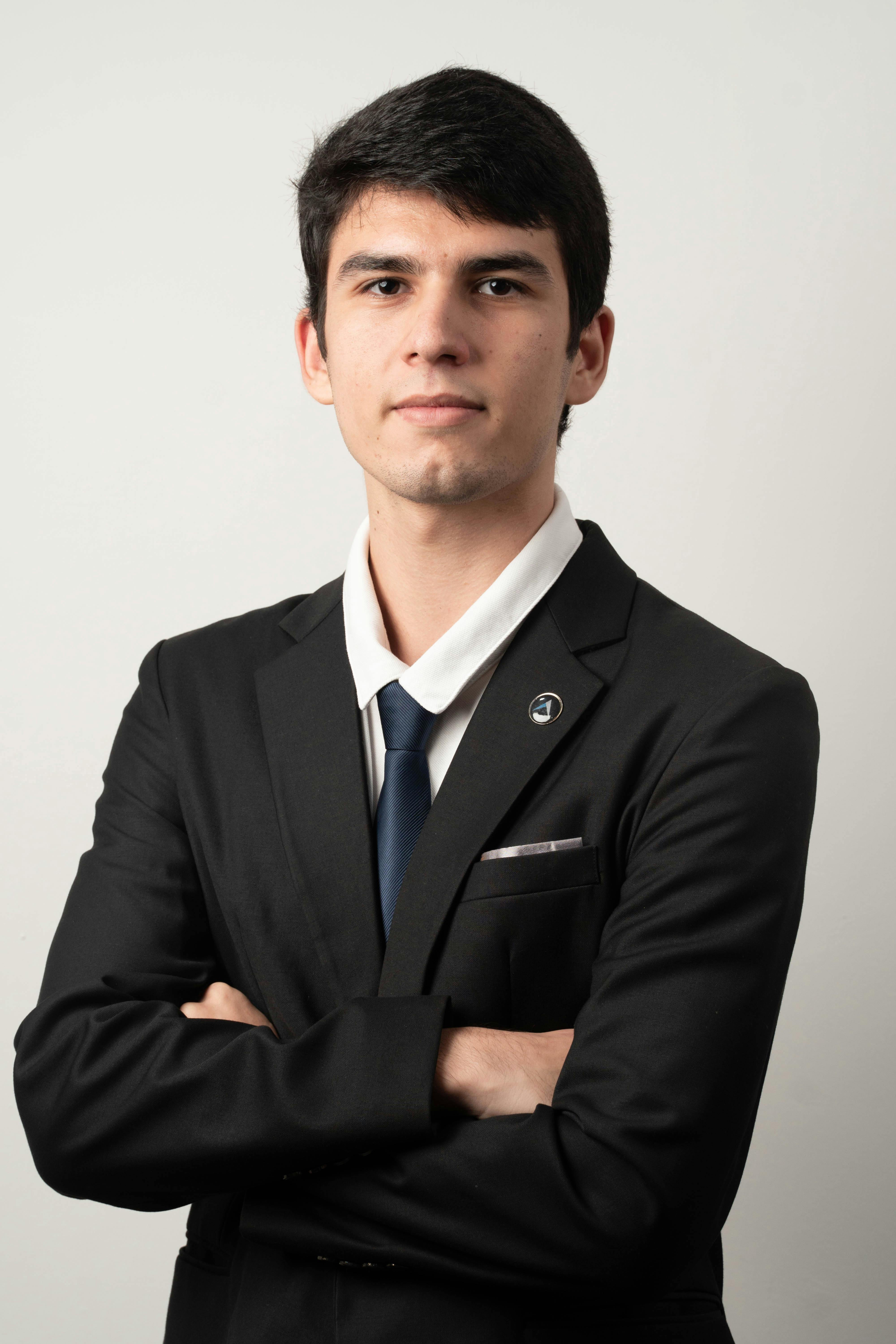Portrait of a confident young man wearing a suit and tie on a white background, exuding elegance and professionalism.