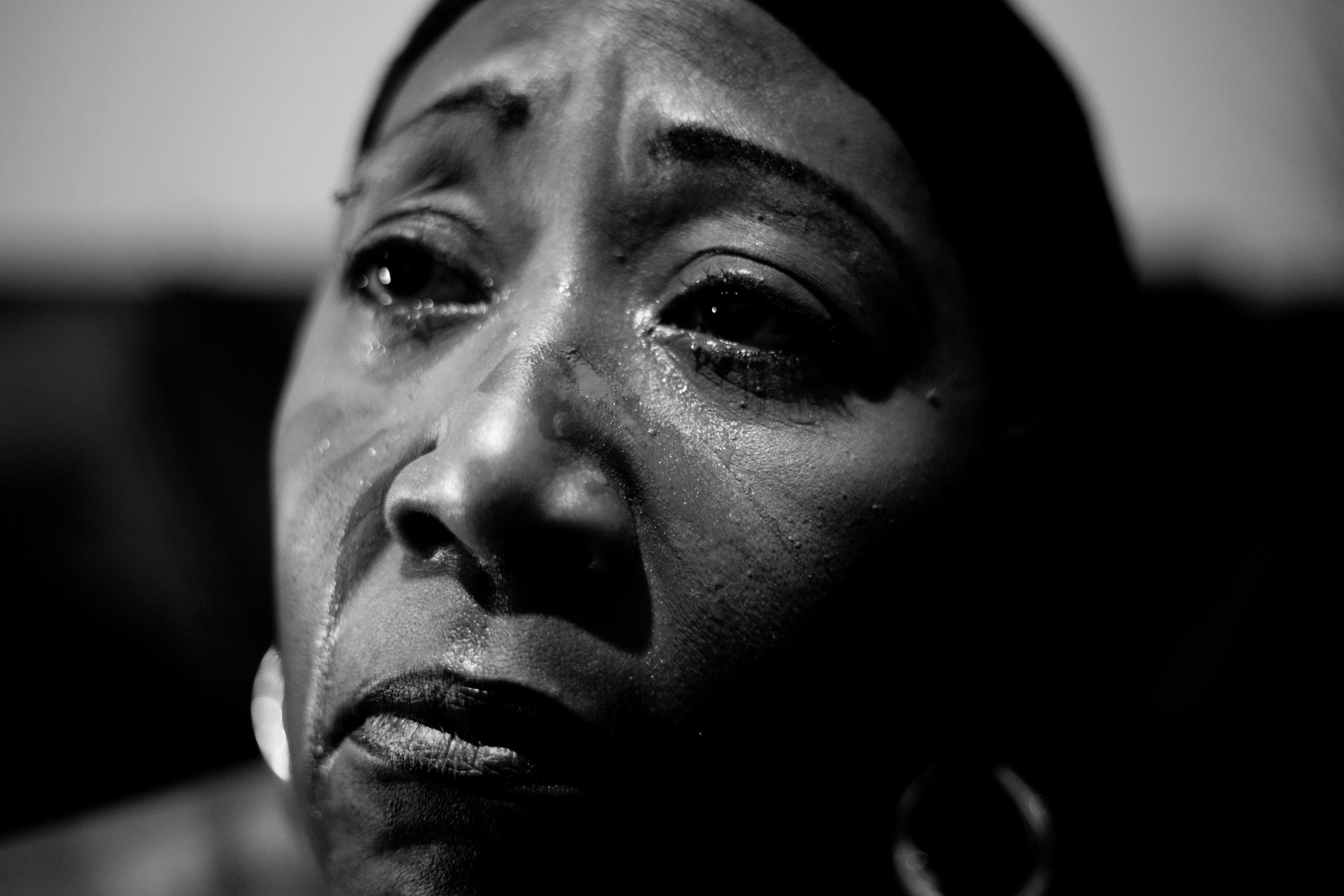 A close-up black and white portrait depicting deep emotion in a woman's face.