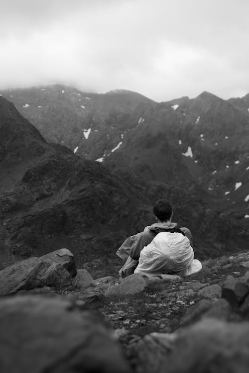 A person sitting on a rock in the mountains