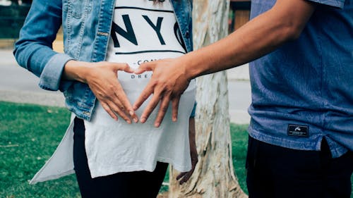 懷孕的婦女抱著她的肚子和旁邊的男人在一起