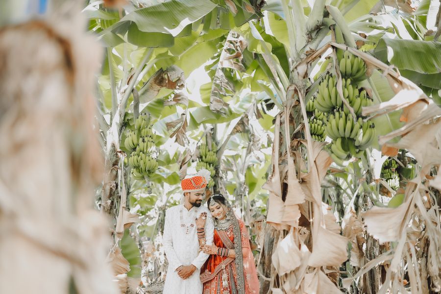 Newlywed Indian couple in traditional attire under banana trees
