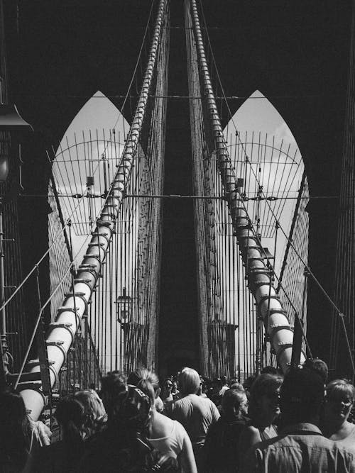 A black and white photo of people walking on the brooklyn bridge