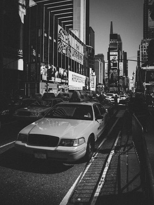 A black and white photo of a taxi in times square
