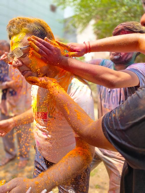 Free People celebrating Holi with colorful powders in a lively outdoor gathering. Stock Photo