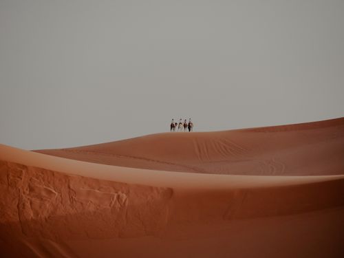 Free A group of people riding camels across vast dunes in Marrakesh, Morocco, showcasing a serene desert landscape. Stock Photo