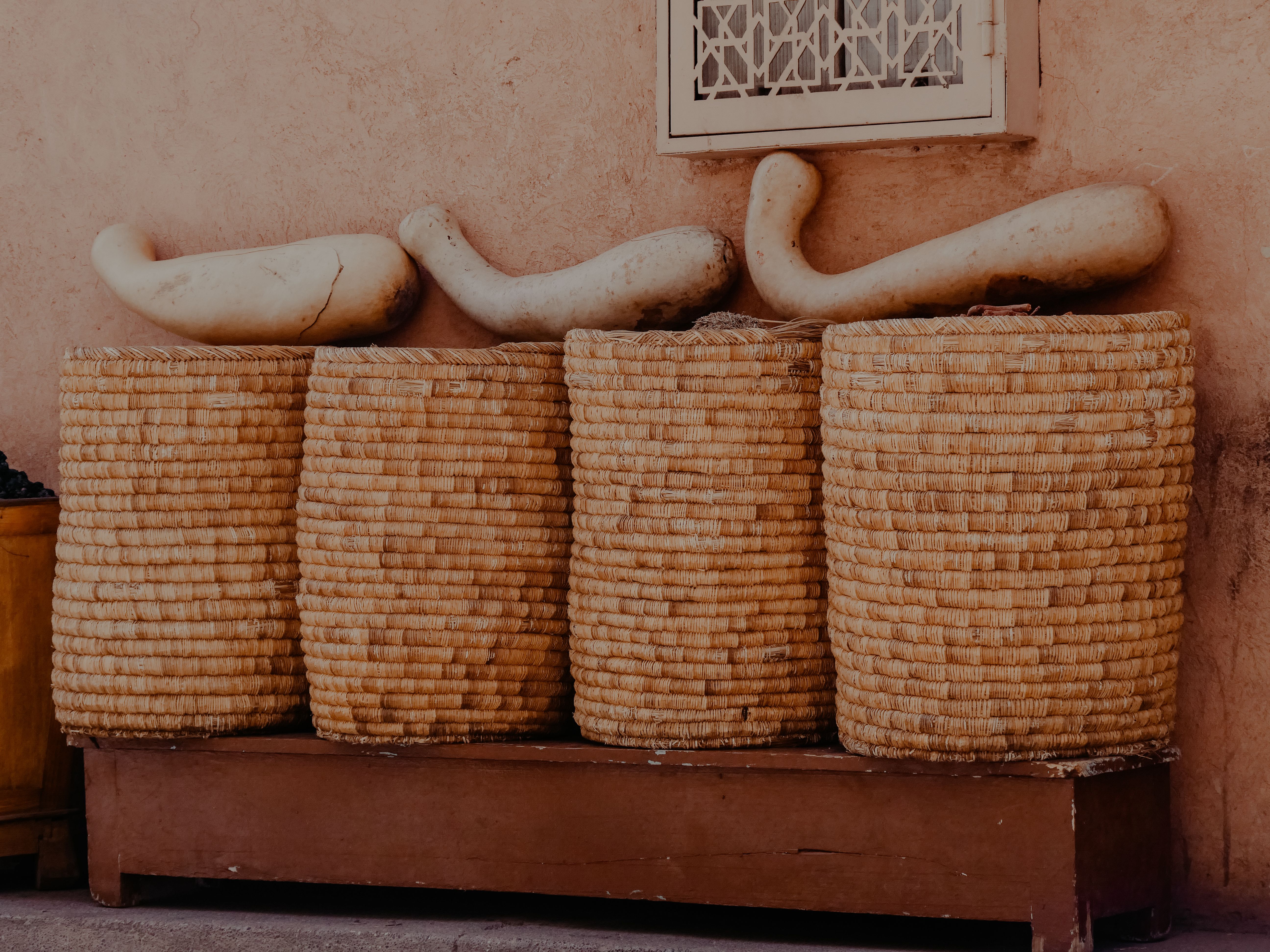 Row of woven baskets with decorative gourds in Marrakesh, showcasing rustic home decor.